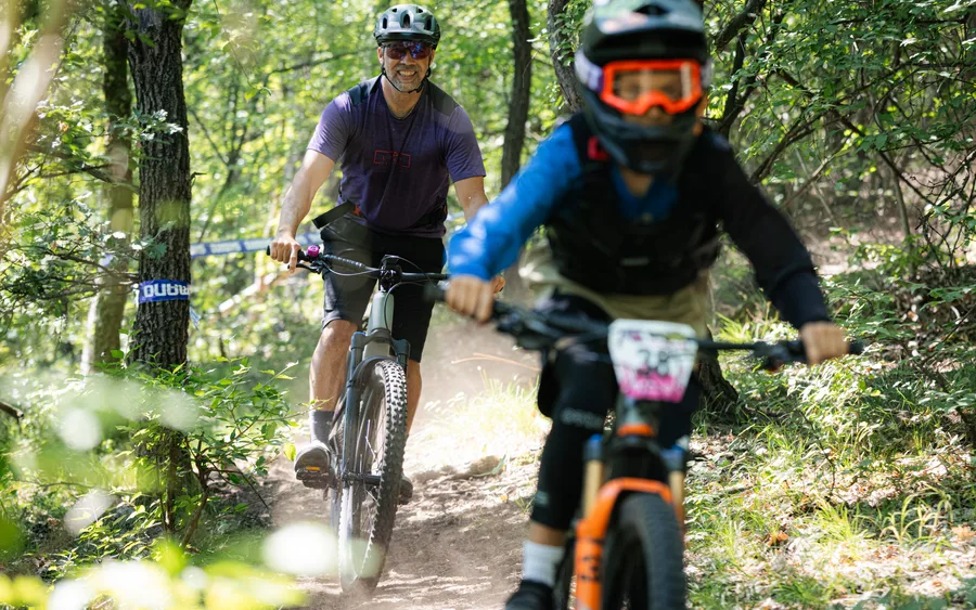 Dvaja usmiati jazdci na lesnom traili počas enduro pretekov