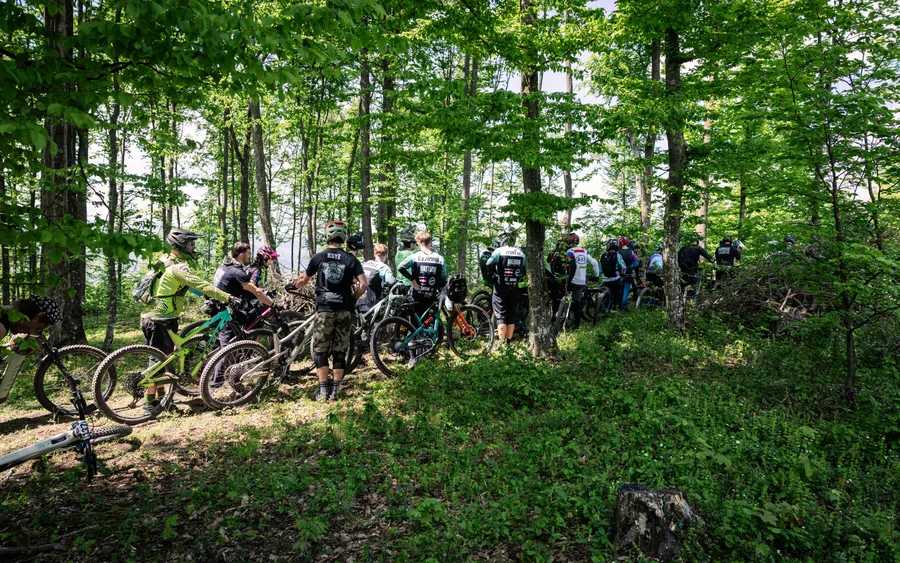 Skupina jazdcov s bicyklami čaká v lese pred štartom rýchlostnej skúšky