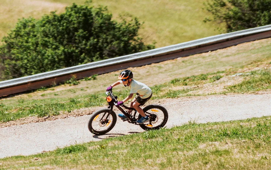 Dieťa v prilbe jazdí na bicykli po traili v MINI bike parku pod pásovým vlekom na Donovaloch
