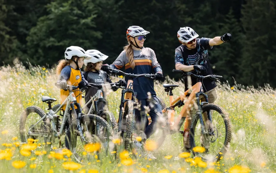 Inštruktor vysvetľuje deťom na bicykloch techniku jazdy na lúke nad Donovalmi